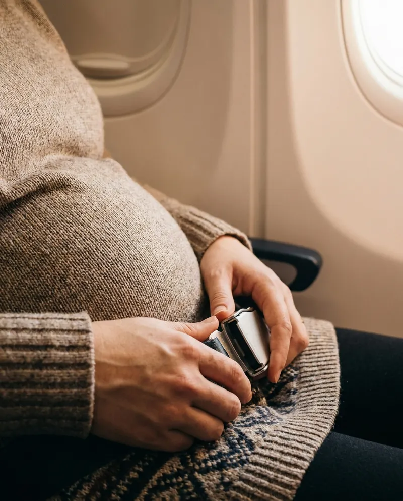 Pregnant woman fastening the airplane lap seatbelt low under her belly